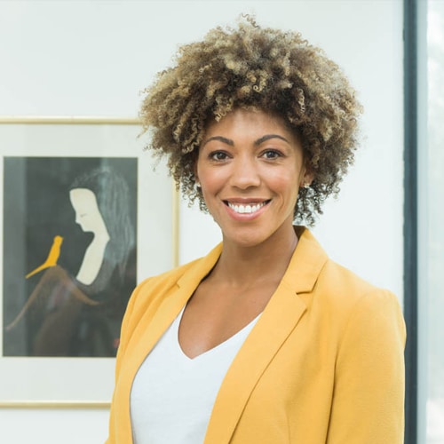 Dr Zoe Williams looks at the camera with a big smile, wearing a yellow suit