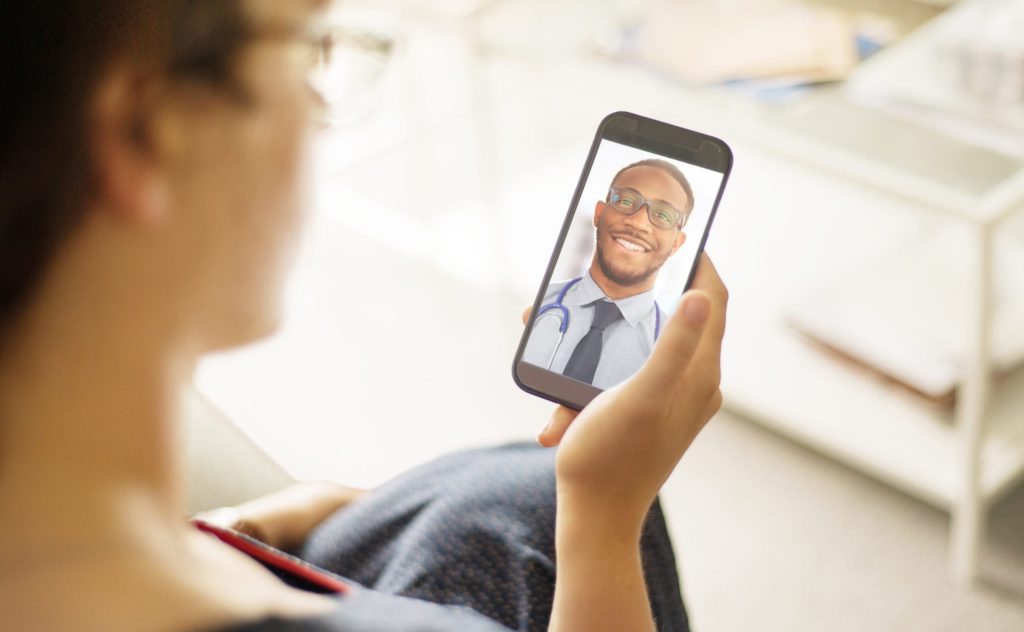 Woman and black doctor having an virtual consultation via a phone