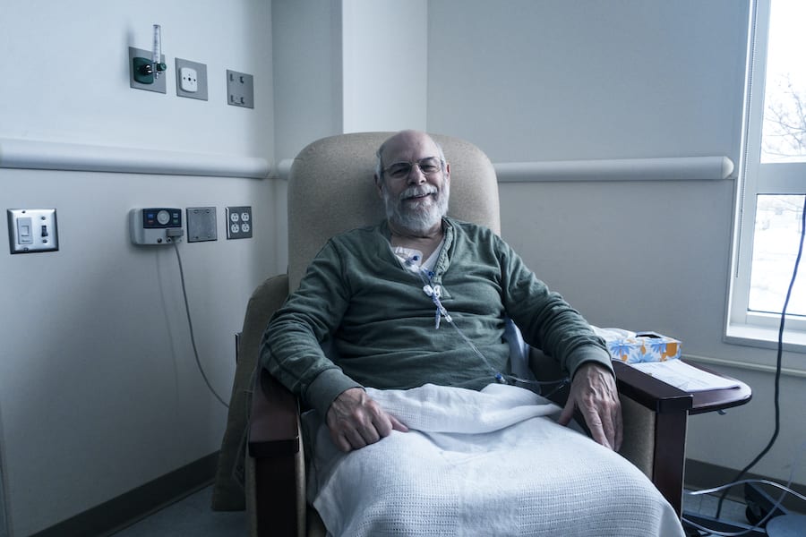 Older white male sitting in hospital chair facing camera