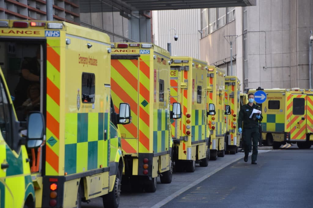A queue of ambulances waits outside a hospital.