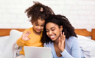 Black woman and black child waving to someone on a virtual call